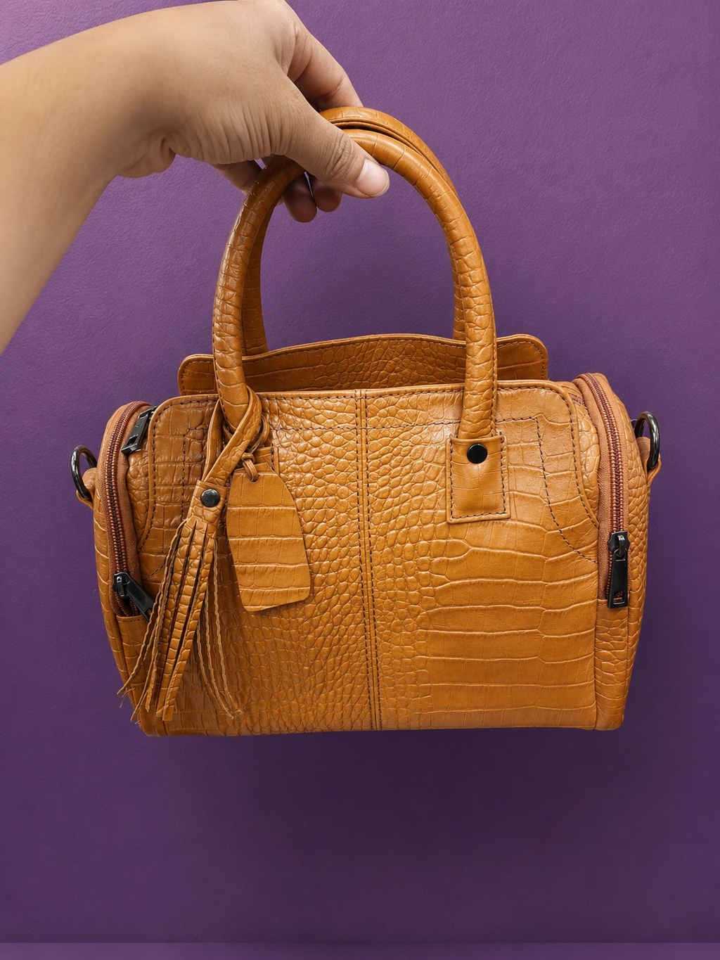 Croco texture tan handbag held up against purple background