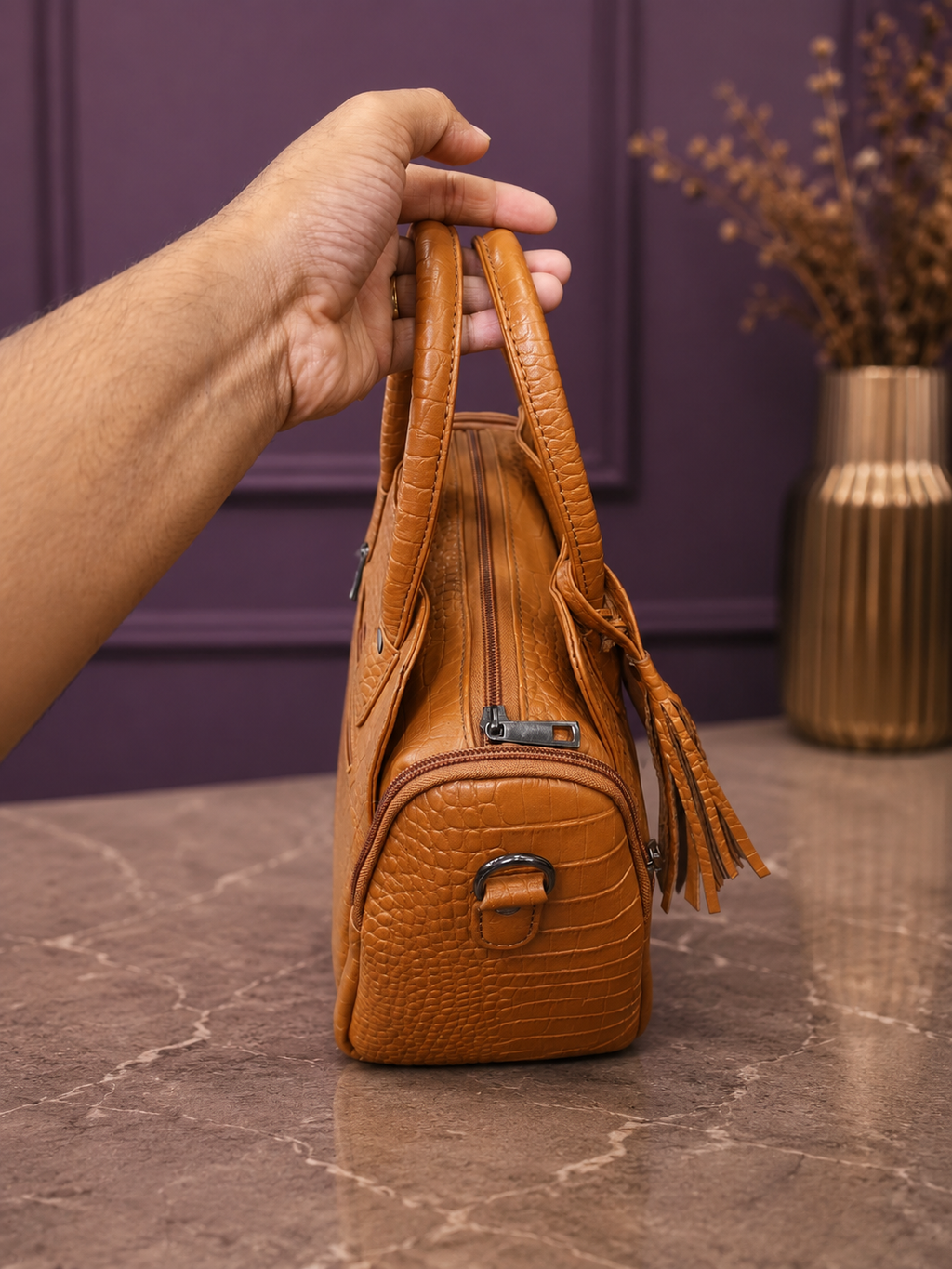 Side view of croco texture tan handbag showing zip pocket and tassel detail