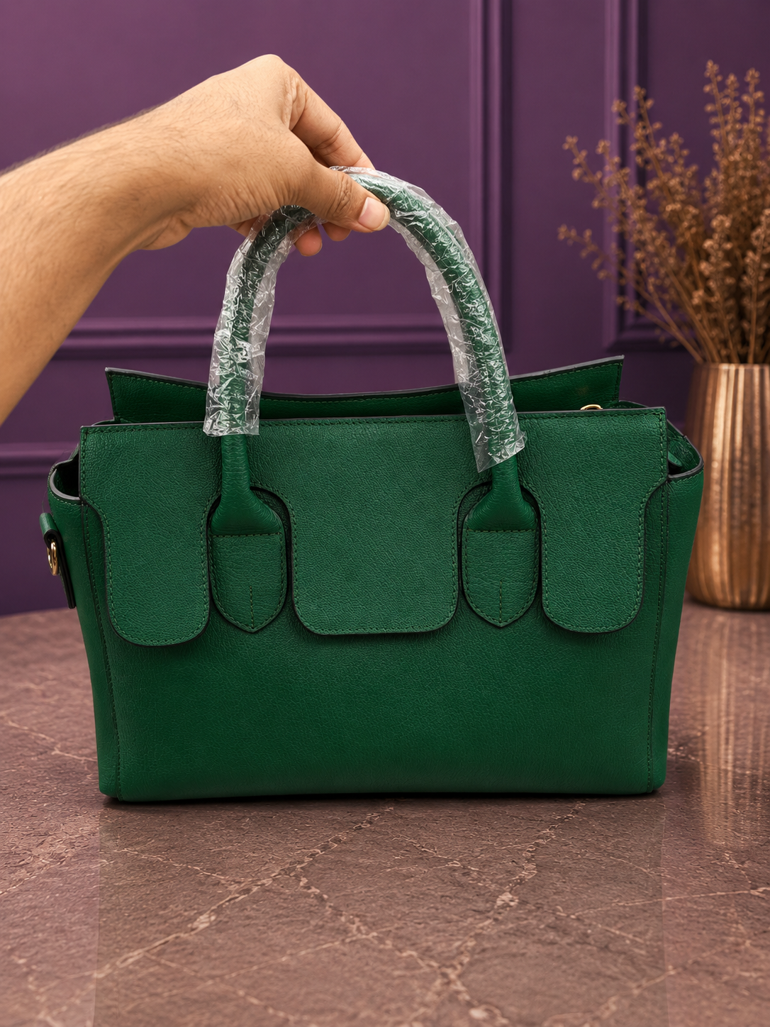 Front view of emerald green structured handbag with purple background
